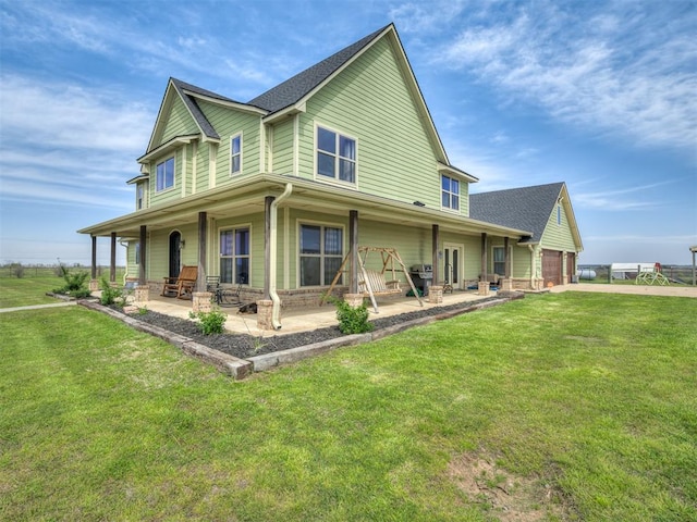 rear view of house featuring a patio area, a yard, and a garage