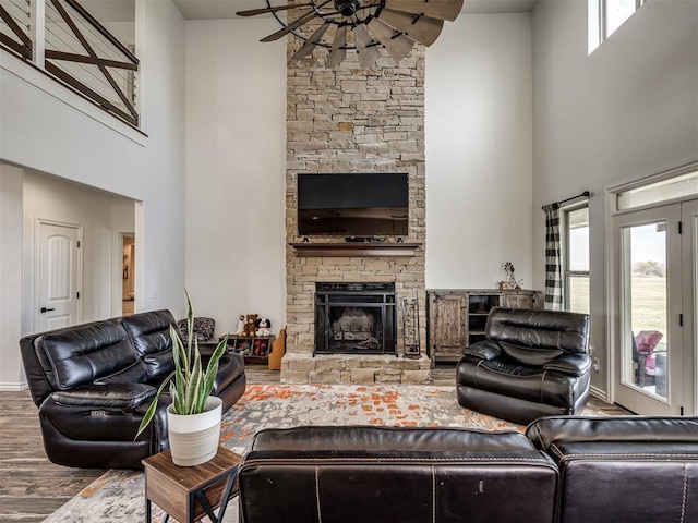 living room with hardwood / wood-style floors, ceiling fan, a fireplace, and a high ceiling