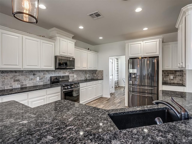 kitchen featuring sink, hanging light fixtures, stainless steel appliances, decorative backsplash, and white cabinets