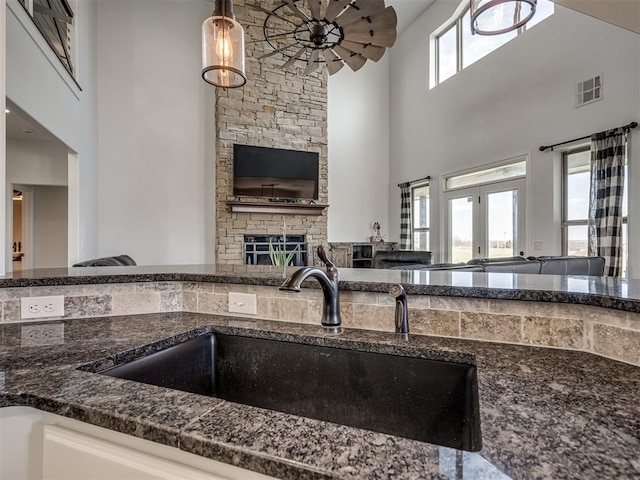 kitchen with pendant lighting, a towering ceiling, sink, and a wealth of natural light