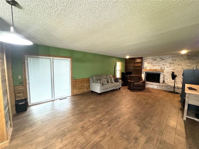 unfurnished living room with a fireplace, wood-type flooring, and a textured ceiling