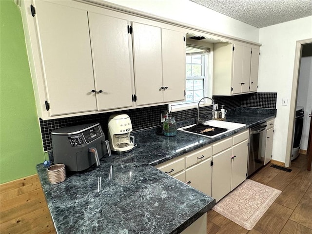 kitchen with backsplash, a textured ceiling, sink, hardwood / wood-style flooring, and dishwasher