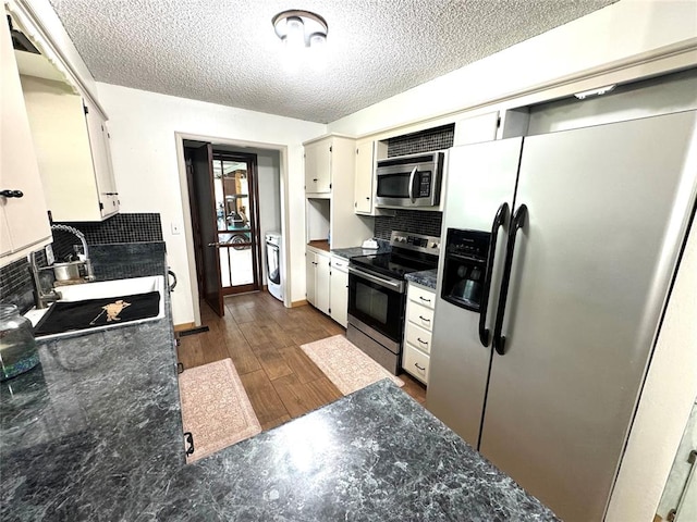 kitchen featuring sink, stainless steel appliances, tasteful backsplash, dark hardwood / wood-style floors, and washer / clothes dryer