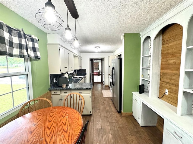 kitchen featuring sink, dark wood-type flooring, stainless steel refrigerator with ice dispenser, pendant lighting, and white cabinets