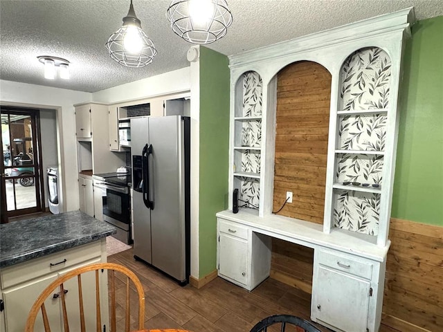 kitchen with stainless steel appliances, dark wood-type flooring, decorative light fixtures, white cabinets, and washer / dryer