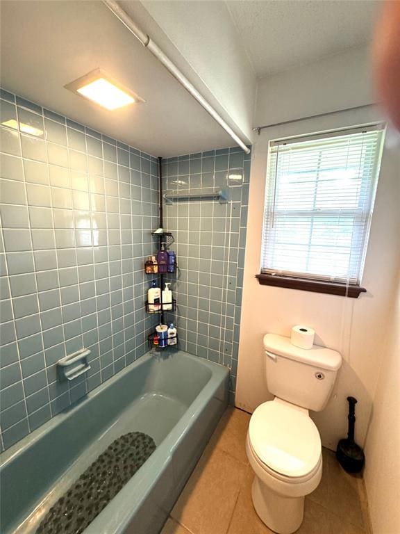 bathroom with tile patterned flooring, toilet, and tiled shower / bath