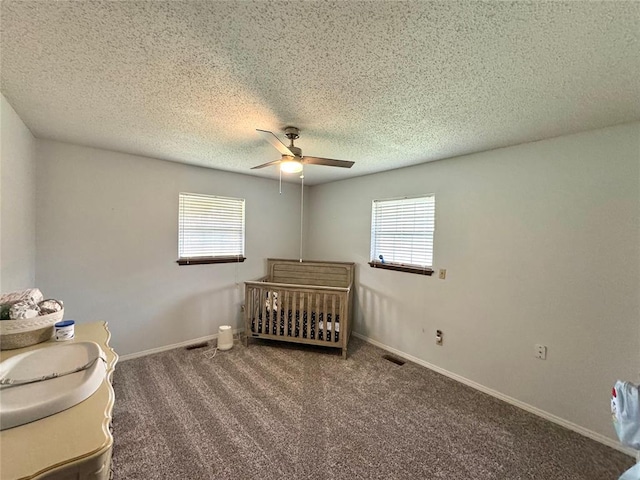 unfurnished bedroom with multiple windows, ceiling fan, and dark carpet