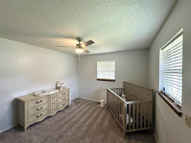 carpeted bedroom featuring a crib, a textured ceiling, and ceiling fan