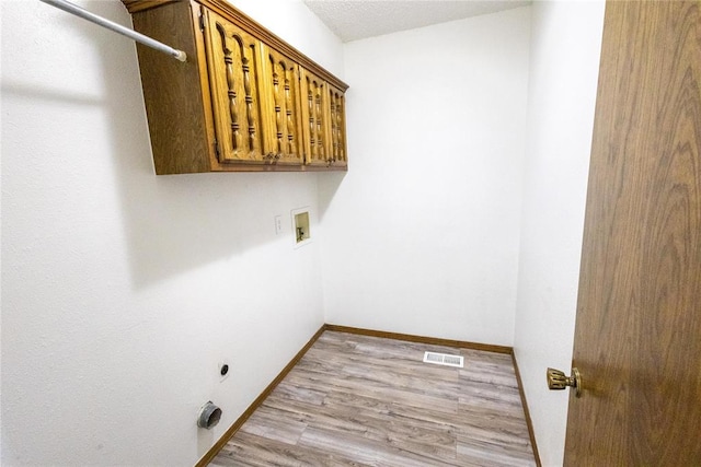 laundry room with washer hookup, cabinets, hookup for an electric dryer, light hardwood / wood-style flooring, and a textured ceiling