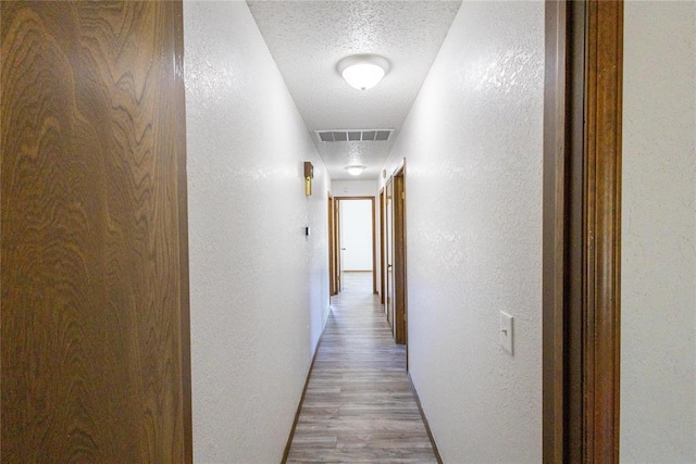 hallway with wood-type flooring and a textured ceiling