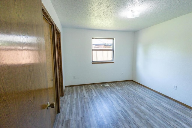 unfurnished bedroom with a textured ceiling, light wood-type flooring, and a closet