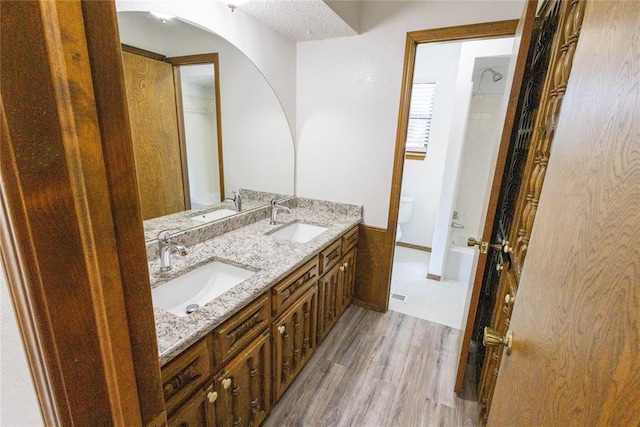 bathroom with wood-type flooring, vanity, a textured ceiling, and toilet