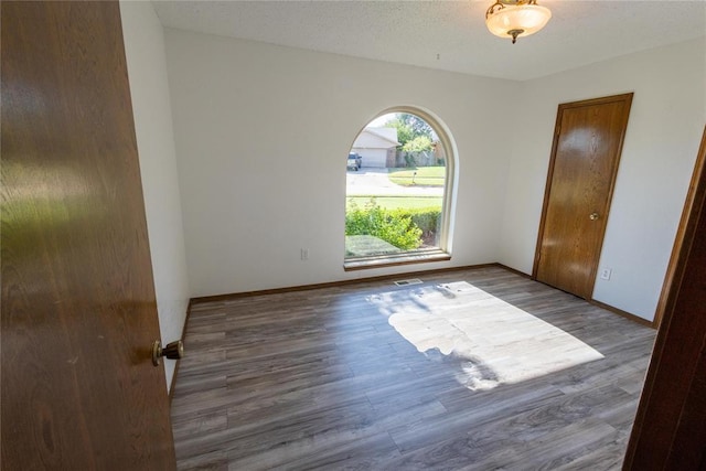 spare room featuring a textured ceiling and dark hardwood / wood-style floors