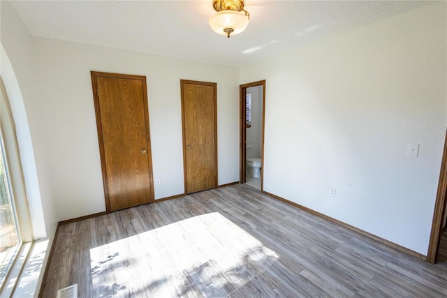 unfurnished bedroom featuring light hardwood / wood-style floors and ensuite bath