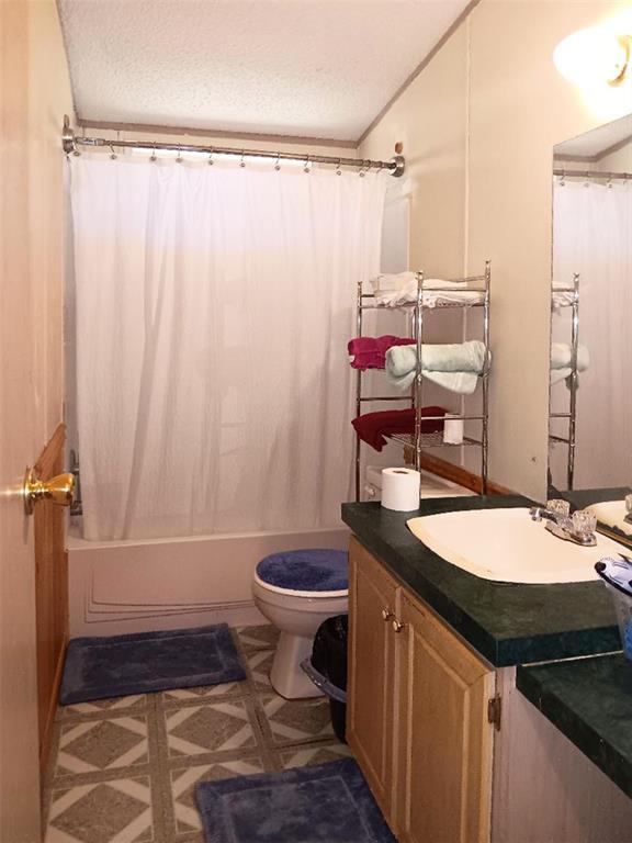33308 S Post Office Nck, Shawnee, OK 74801 - full bath with vanity, toilet, shower / tub combo with curtain, and a textured ceiling