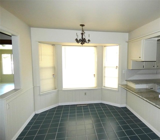 unfurnished dining area with a chandelier and dark tile patterned floors