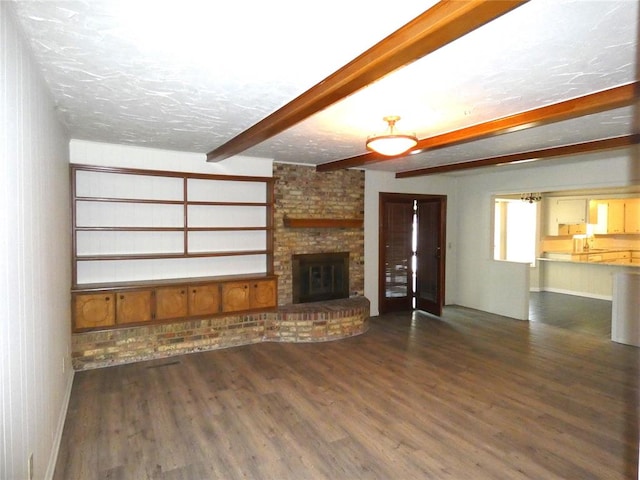 unfurnished living room with beamed ceiling, a fireplace, dark wood-type flooring, and a textured ceiling