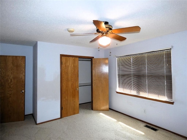 unfurnished bedroom featuring a textured ceiling, ceiling fan, light carpet, and a closet