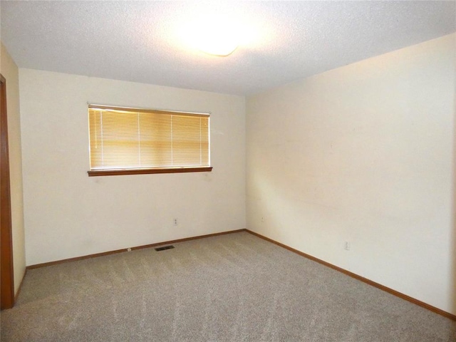 carpeted empty room with a textured ceiling