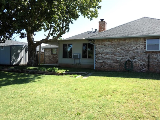 rear view of property featuring a storage unit and a yard