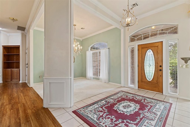 tiled foyer entrance featuring crown molding and an inviting chandelier