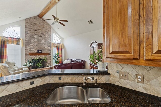 kitchen featuring tasteful backsplash, a wealth of natural light, dark stone countertops, and sink