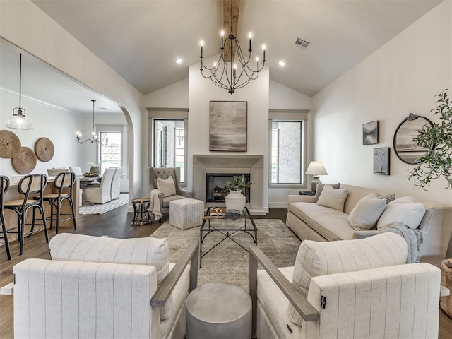 living room featuring vaulted ceiling with beams, dark hardwood / wood-style floors, a wealth of natural light, and a chandelier