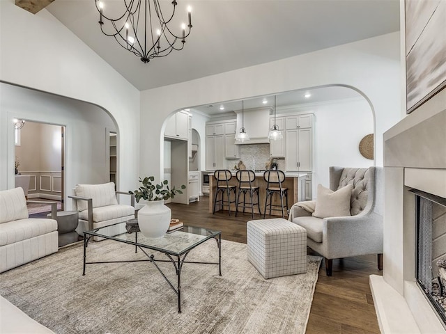 living room with high vaulted ceiling, dark wood-type flooring, and a notable chandelier