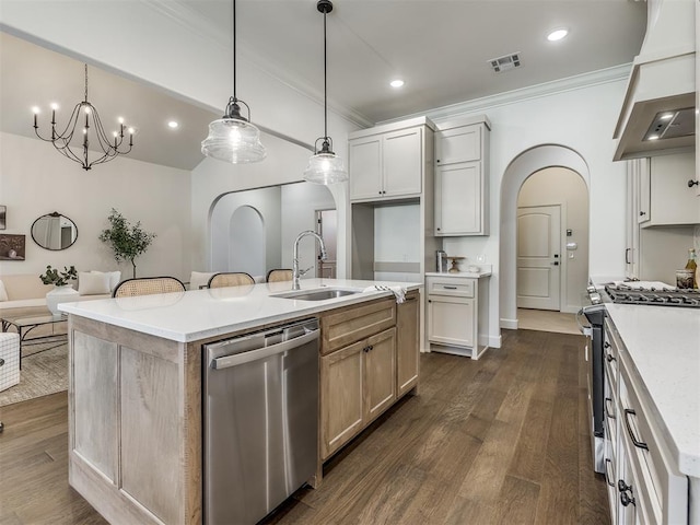 kitchen with appliances with stainless steel finishes, sink, pendant lighting, a center island with sink, and white cabinetry