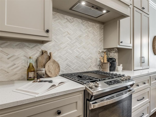 kitchen with tasteful backsplash, light stone counters, premium range hood, high end stove, and white cabinetry