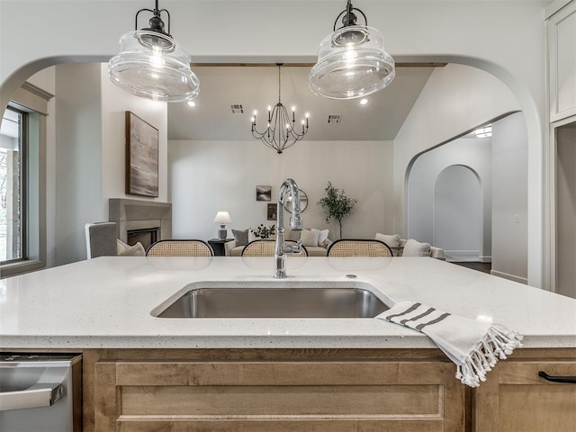 kitchen with decorative light fixtures, light stone countertops, sink, and an inviting chandelier