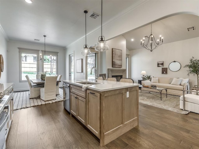 kitchen with a center island with sink, hanging light fixtures, dark wood-type flooring, and sink