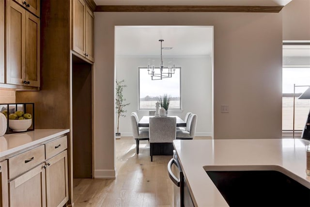 kitchen featuring dishwasher, light hardwood / wood-style flooring, ornamental molding, decorative light fixtures, and a chandelier