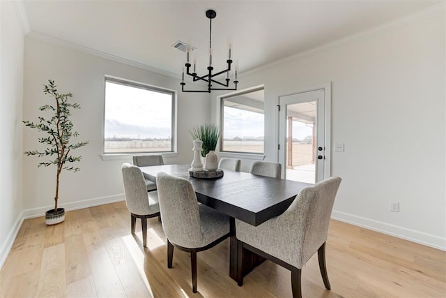 dining space with light wood-type flooring, ornamental molding, and a notable chandelier