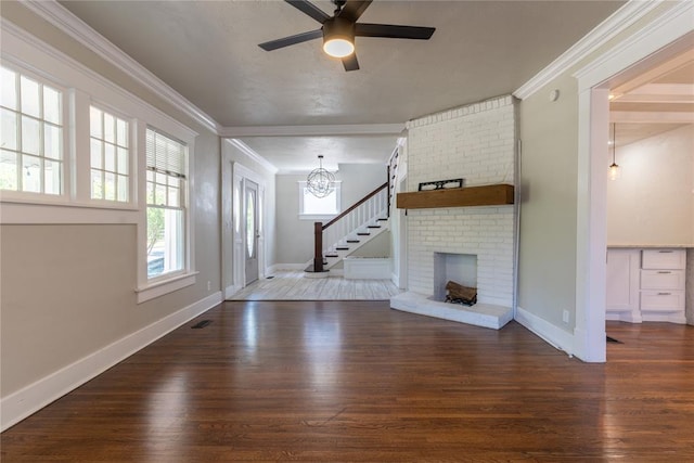 unfurnished living room featuring dark hardwood / wood-style floors, a fireplace, crown molding, and ceiling fan with notable chandelier