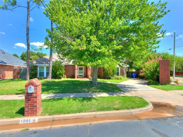 view of property hidden behind natural elements featuring a front lawn