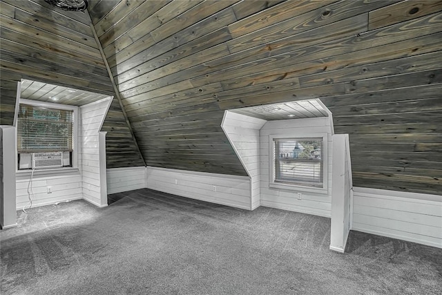 bonus room featuring dark colored carpet, wood walls, and vaulted ceiling