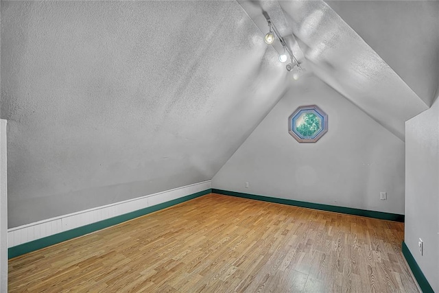 additional living space featuring hardwood / wood-style floors, a textured ceiling, and lofted ceiling