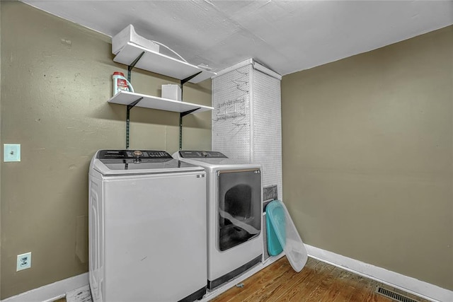 clothes washing area with washer and dryer and wood-type flooring