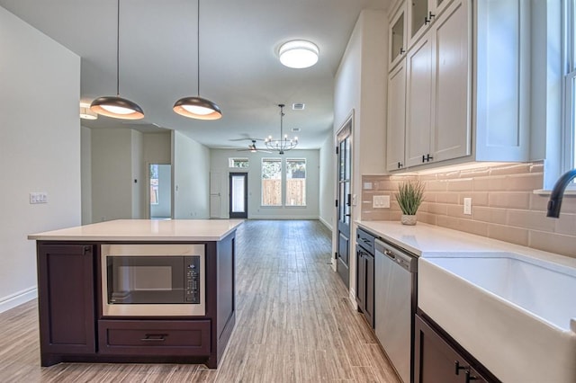 kitchen with sink, white cabinets, hanging light fixtures, and appliances with stainless steel finishes