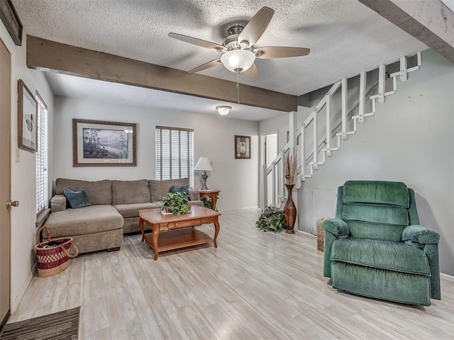 living room featuring ceiling fan, beam ceiling, a textured ceiling, and light hardwood / wood-style flooring