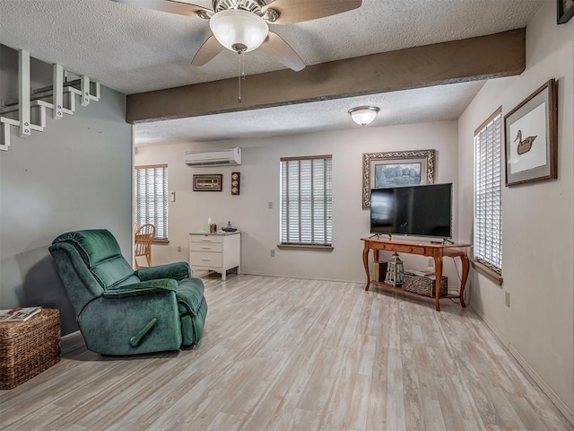 living area with a wall mounted air conditioner, plenty of natural light, light hardwood / wood-style floors, and beamed ceiling