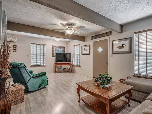 living room featuring plenty of natural light, beamed ceiling, a textured ceiling, and light wood-type flooring