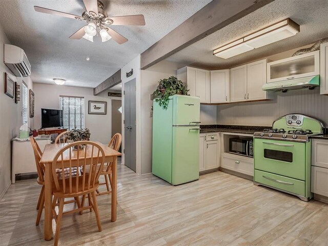 kitchen featuring beam ceiling, a wall mounted air conditioner, light hardwood / wood-style flooring, gas range oven, and white refrigerator