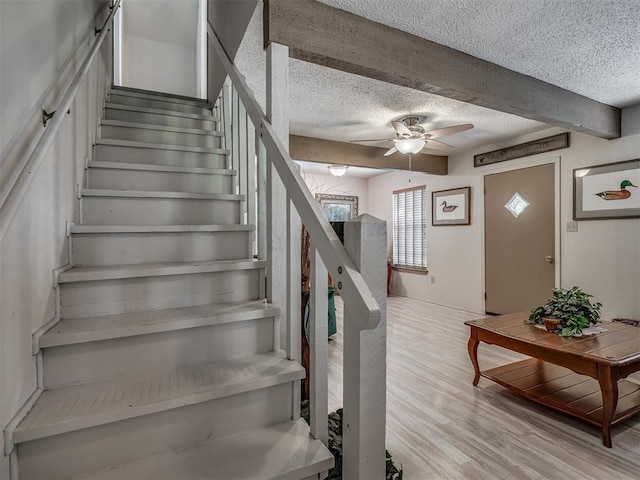 stairs featuring hardwood / wood-style floors, a textured ceiling, and ceiling fan