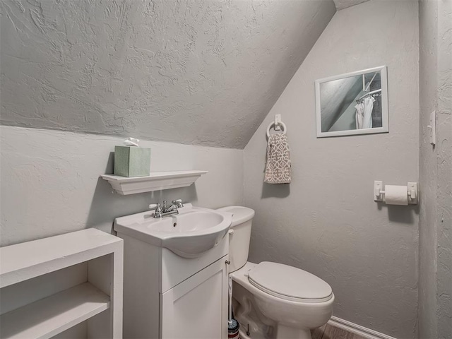 bathroom featuring vanity, toilet, and lofted ceiling