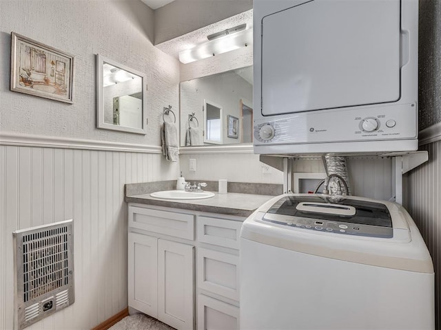 washroom with heating unit, stacked washer and dryer, and sink