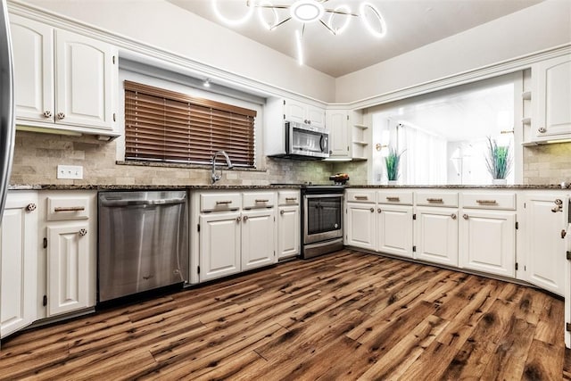 kitchen with dark stone countertops, appliances with stainless steel finishes, dark hardwood / wood-style flooring, and white cabinets