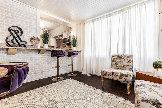 sitting room with brick wall, dark hardwood / wood-style floors, and wooden ceiling