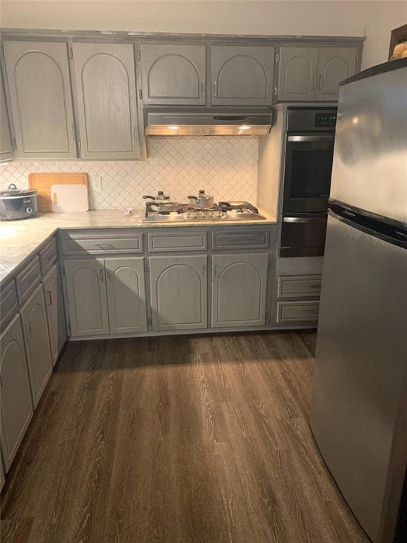 kitchen featuring backsplash, gray cabinets, dark wood-type flooring, and appliances with stainless steel finishes